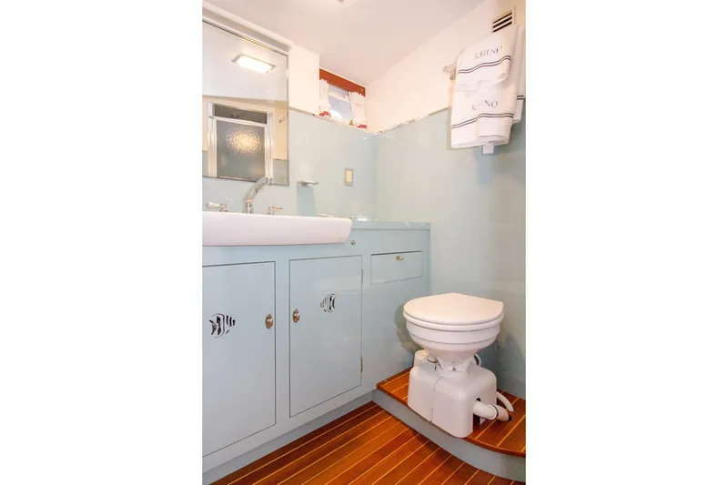 Slide: The Image of Vintage 1958 Rybovich 54 Yachtfish bathroom with light blue cabinetry and wooden flooring. - 13