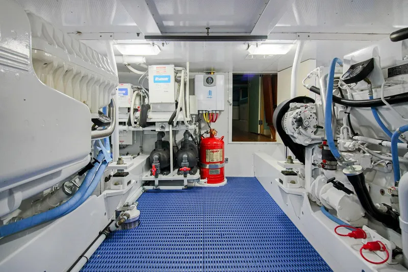 Slide: The Image of Engine room of 1958 Rybovich 54 Yachtfish, featuring modern equipment and blue flooring. - 18