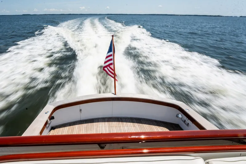 Slide: The Image of 1958 Rybovich 54 Yachtfish cruising, leaving a wake, with American flag displayed. - 12