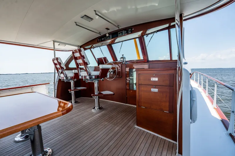 Slide: The Image of 1958 Rybovich 54 Yachtfish interior with wooden helm, chairs, and ocean view. - 8