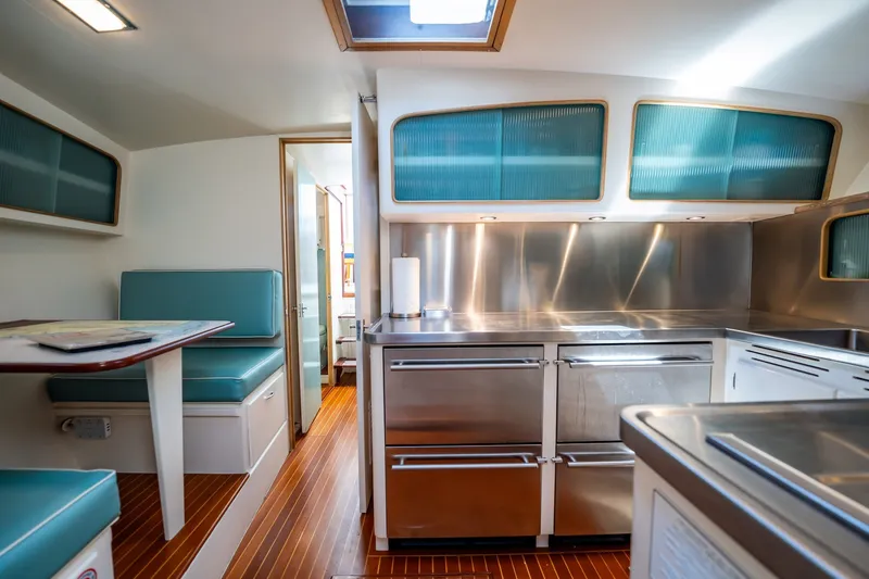 Slide: The Image of Interior of 1958 Rybovich 54 Yachtfish, featuring modern kitchen and dining area with teal accents. - 14