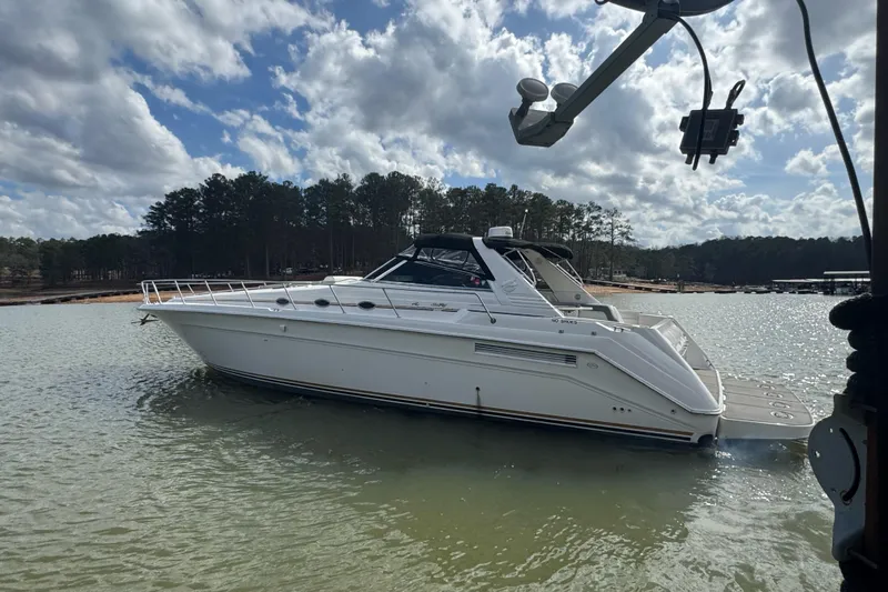 The Image of 1996 Sea Ray 500 Sedan Bridge yacht on calm water under a cloudy sky. - 0