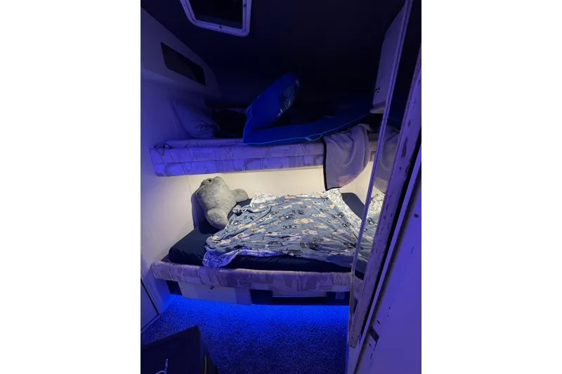 Slide: The Image of Cozy bunk beds with blue lighting in a 1996 Sea Ray 500 Sedan Bridge cabin. - 24