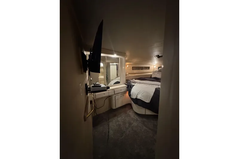 Slide: The Image of 1996 Sea Ray 500 Sedan Bridge cabin interior with bed, TV, and vanity area. - 25