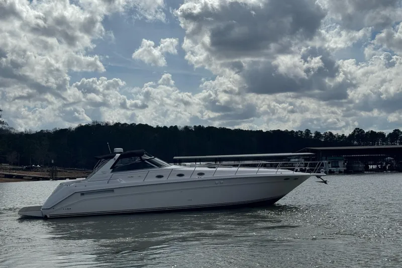 Slide: The Image of 1996 Sea Ray 500 Sedan Bridge yacht on a calm lake under cloudy skies. - 7