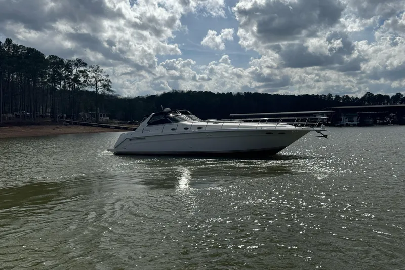 Slide: The Image of 1996 Sea Ray 500 Sedan Bridge yacht on a serene lake under cloudy skies. - 8