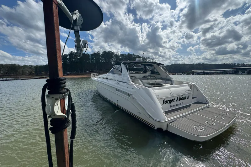 Slide: The Image of 1996 Sea Ray 500 Sedan Bridge yacht on a serene lake under a cloudy sky. - 9