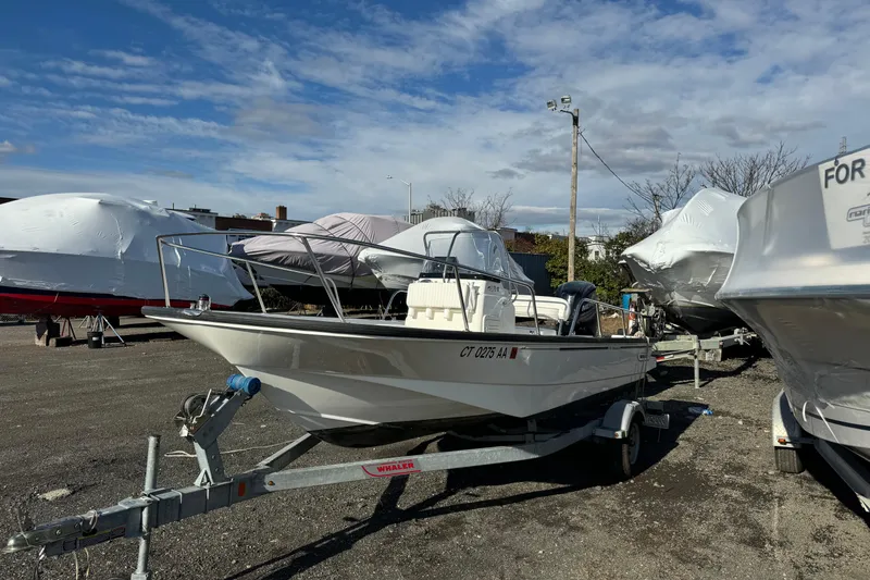 Slide: The Image of 2015 Boston Whaler 170 Montauk boat on trailer, parked outdoors under a blue sky. - 1