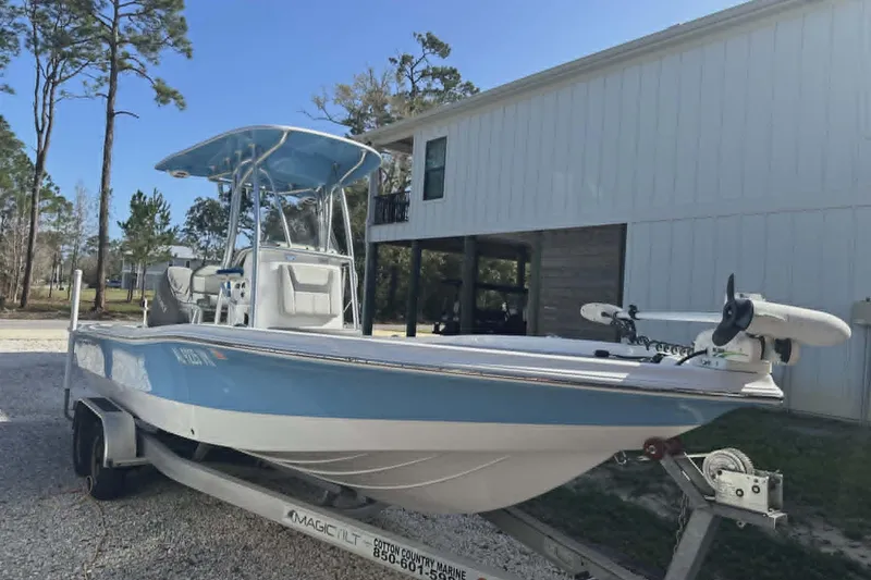 Slide: The Image of 2022 Aquasport 244 Bay boat on trailer, parked near a white building. - 1