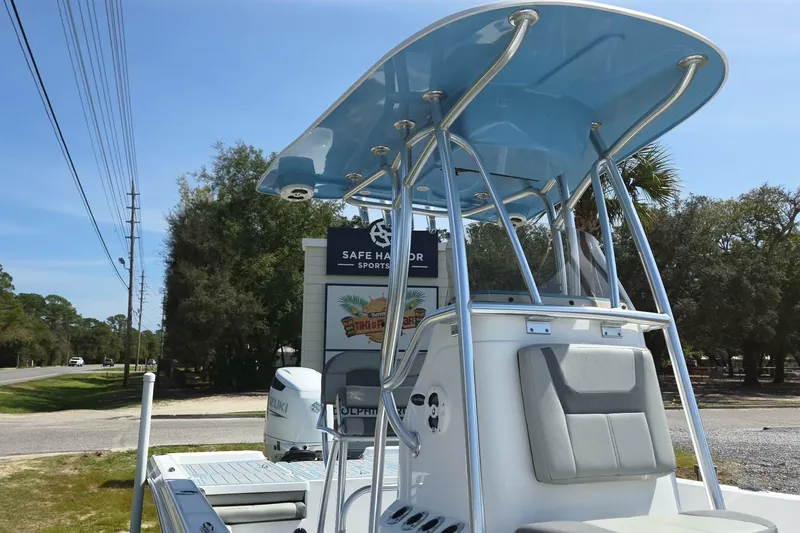 Slide: The Image of 2022 Aquasport 244 Bay boat with T-top and Suzuki engine, parked outdoors. - 2