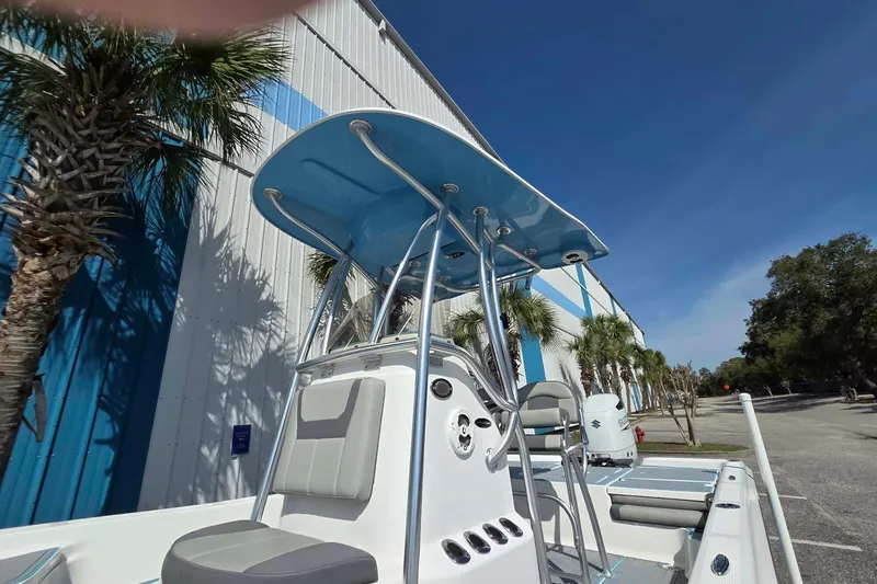 Slide: The Image of 2022 Aquasport 244 Bay boat with T-top, parked near palm trees and blue building. - 4