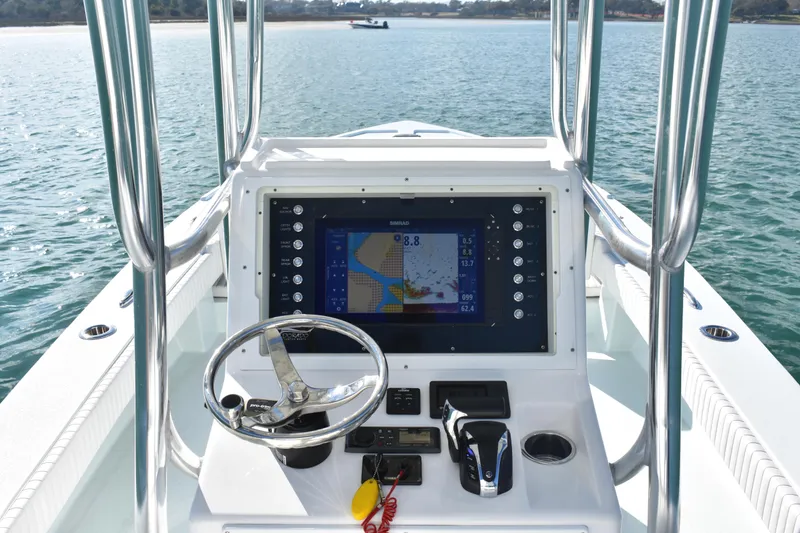 Slide: The Image of 2023 Dorado 25 boat console with navigation display and steering wheel on calm water. - 10