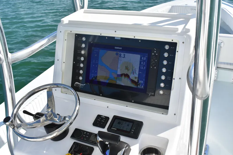 Slide: The Image of 2023 Dorado 25 boat dashboard with navigation system and steering wheel on open water. - 11