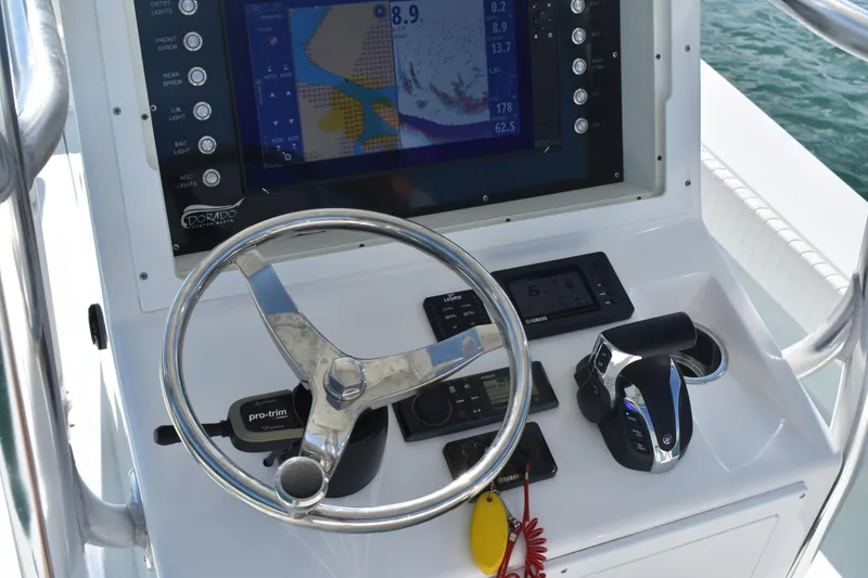 Slide: The Image of 2023 Dorado 25 boat dashboard with steering wheel, controls, and navigation display. - 12