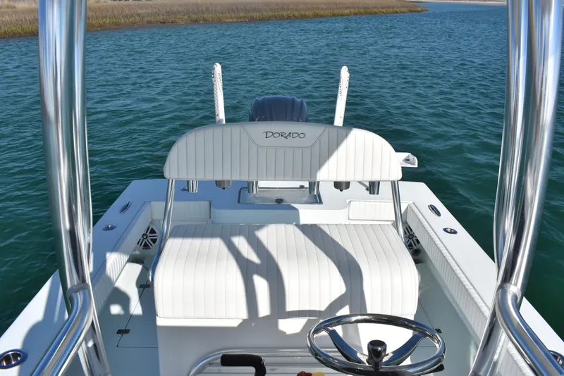 Slide: The Image of 2023 Dorado 25 boat interior with white seating and steering wheel on open water. - 13