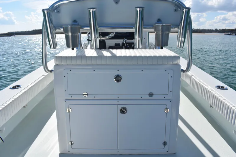 Slide: The Image of 2023 Dorado 25 boat interior with storage compartments and rod holders on a sunny day. - 16