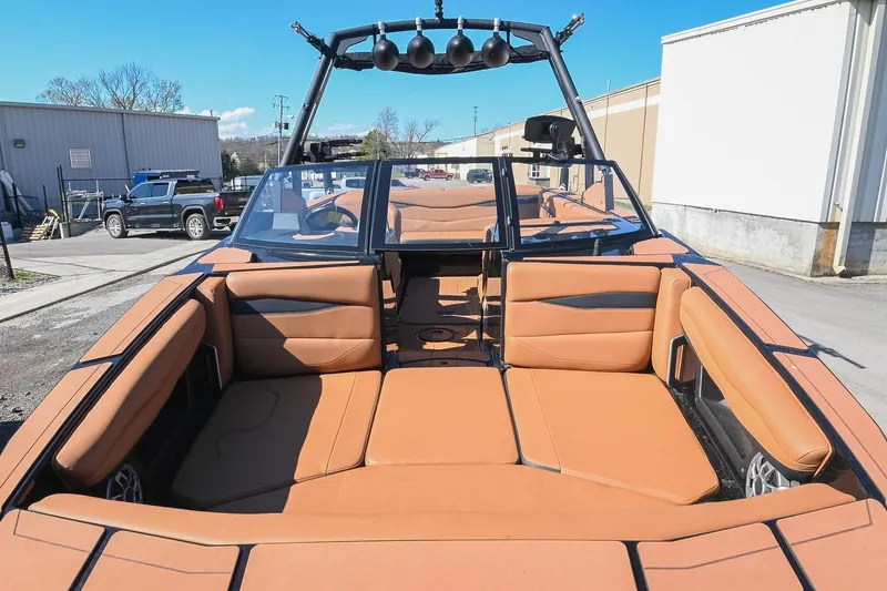 Slide: The Image of 2023 Axis A225 boat with tan interior, parked outdoors under clear blue sky. - 11