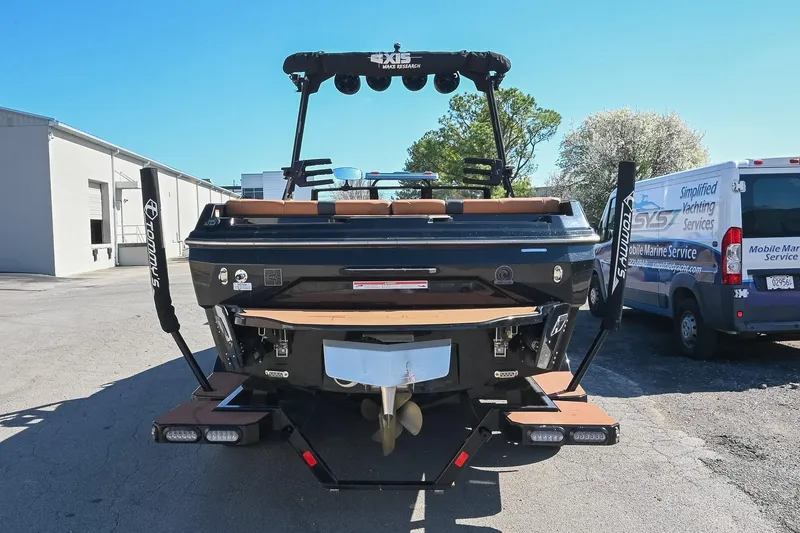 Slide: The Image of 2023 Axis A225 boat rear view, parked near service van, showcasing sleek design. - 4