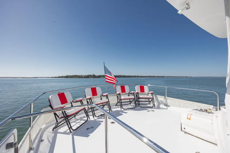 Slide: The Image of 2007 Hatteras 64 Motor Yacht deck with chairs and American flag on calm water. - 16