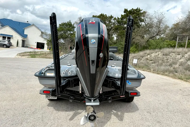 Slide: The Image of 2023 Bass Cat Jaguar STS boat with powerful outboard motor, parked on a driveway. - 13