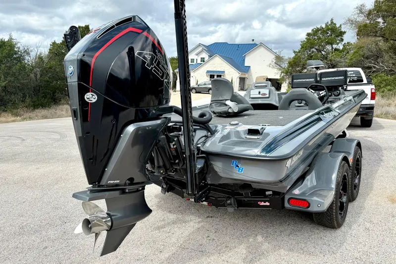 Slide: The Image of 2023 Bass Cat Jaguar STS boat with powerful outboard motor, parked on a residential street. - 14