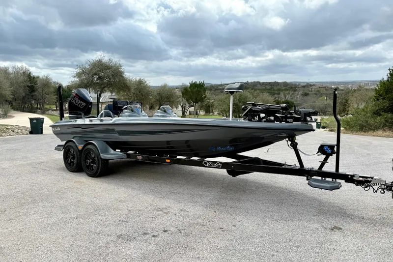 Slide: The Image of 2023 Bass Cat Jaguar STS boat on trailer, parked outdoors under cloudy sky. - 16