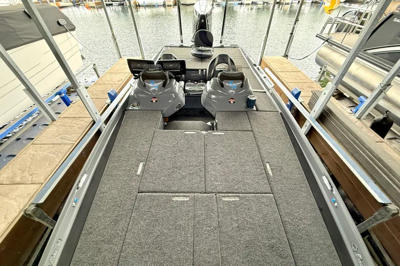 Slide: The Image of 2023 Bass Cat Jaguar STS boat interior with spacious deck and seating at a marina. - 17