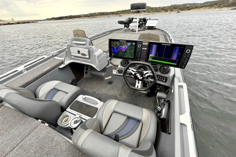 Slide: The Image of 2023 Bass Cat Jaguar STS boat interior with advanced navigation displays on a lake. - 21