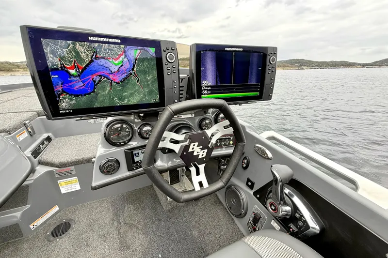 Slide: The Image of 2023 Bass Cat Jaguar STS boat dashboard with dual Humminbird displays on a lake. - 23
