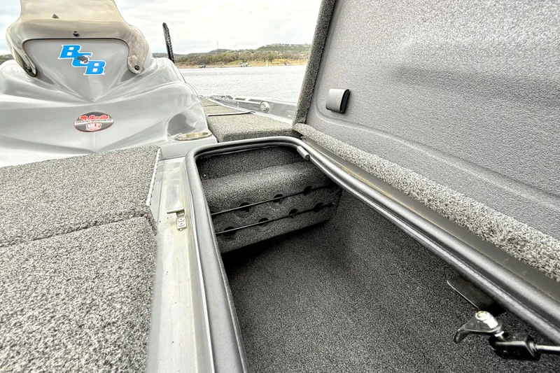 Slide: The Image of 2023 Bass Cat Jaguar STS boat storage compartment with carpeted interior and secure latch. - 28