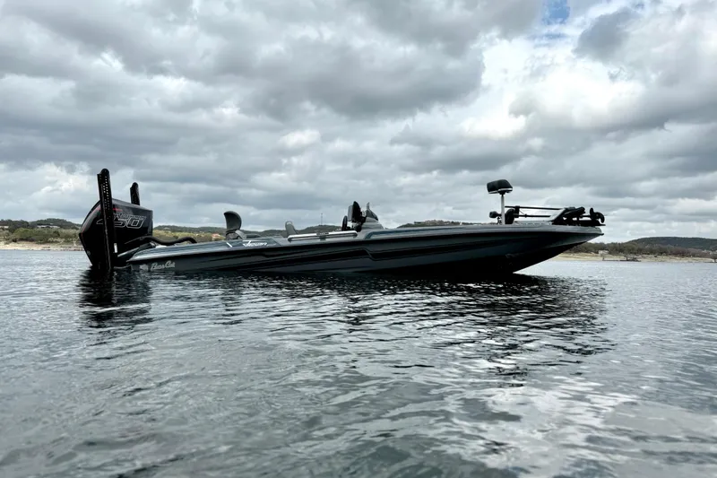 Slide: The Image of 2023 Bass Cat Jaguar STS boat on a calm lake under cloudy skies. - 6