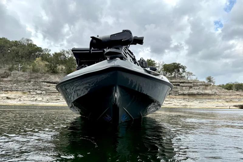 Slide: The Image of 2023 Bass Cat Jaguar STS boat on water, rocky shoreline background. - 8