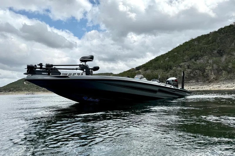 Slide: The Image of 2023 Bass Cat Jaguar STS boat on a serene lake with cloudy sky backdrop. - 9