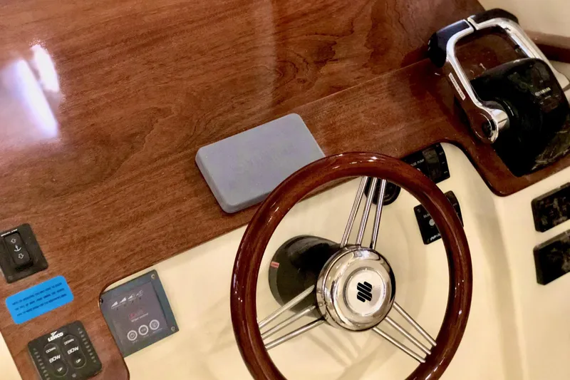 Slide: The Image of Manufacturer Provided Image: Steering wheel and controls of 2026 NorthCoast 315 HT boat, featuring wood finish. - 13