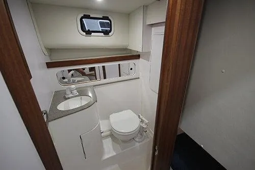 Slide: The Image of Manufacturer Provided Image: 2026 NorthCoast 315 HT boat bathroom with sink, toilet, and porthole window. - 16