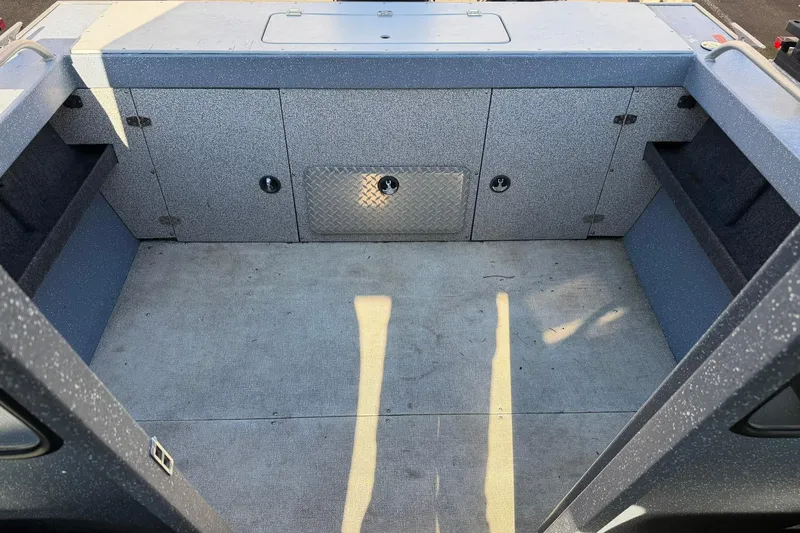 Slide: The Image of 2016 Raider 182 Pro Sport boat interior with storage compartments and carpeted floor. - 12
