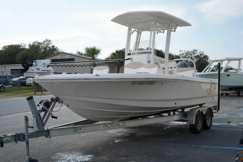 The Image of 2020 Robalo 226 Cayman boat on trailer, parked outdoors, featuring Minn Kota trolling motor. - 0