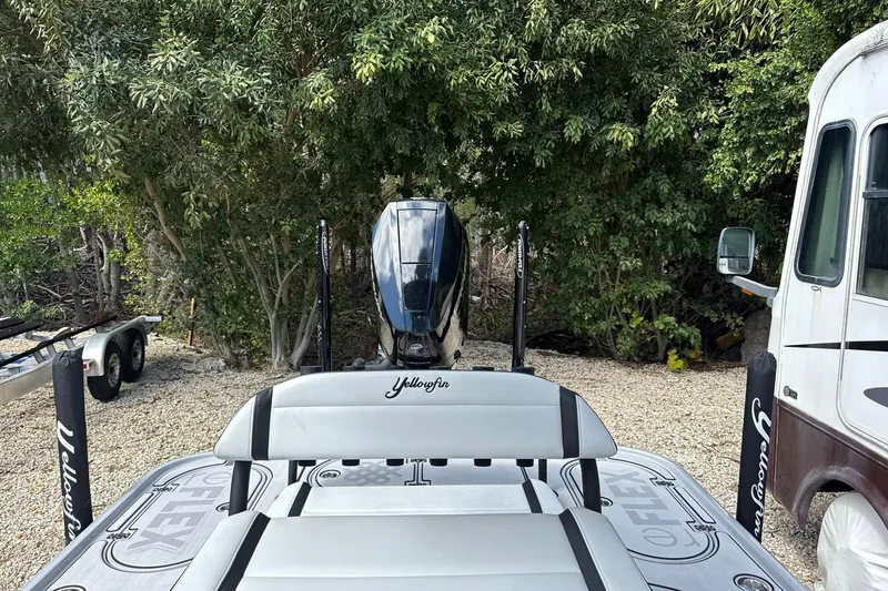 Slide: The Image of 2026 Yellowfin 24 Bay CE boat with outboard motor, parked near trees. - 10