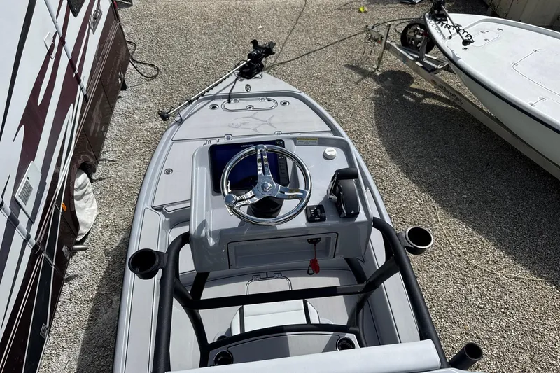 Slide: The Image of 2026 Yellowfin 24 Bay CE boat with steering wheel, parked on gravel. - 7