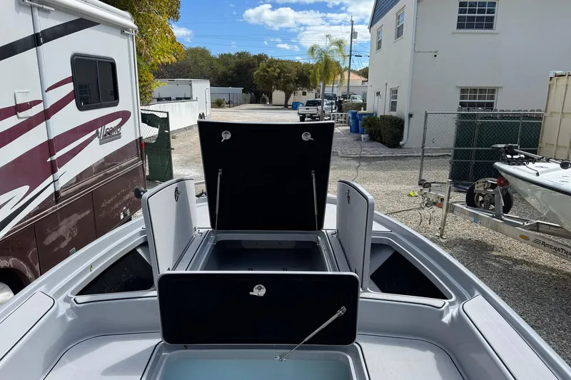 Slide: The Image of 2026 Yellowfin 24 Bay CE boat with open storage compartments, parked outdoors. - 9