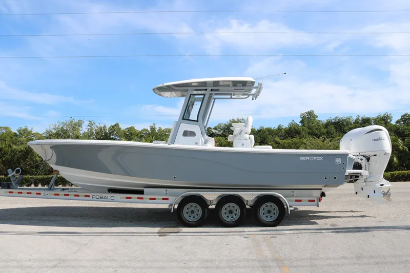 The Image of 2026 Sea Fox 282 Hybrid LT boat on a Robalo trailer, parked outdoors. - 1