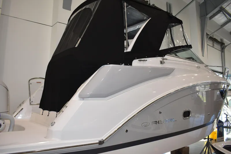 Slide: The Image of 2026 Regal 26 XO boat with black canopy in indoor showroom. - 1