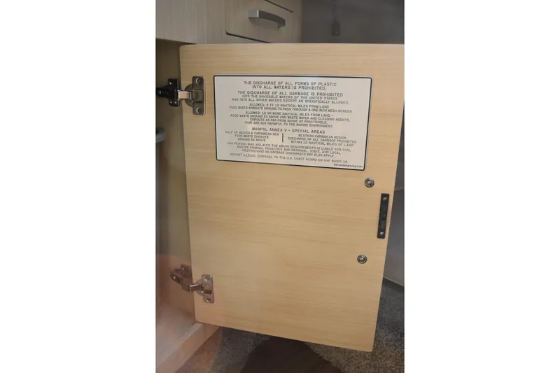 Slide: The Image of Open cabinet door with waste disposal regulations on a 2026 Regal 26 XO boat. - 39