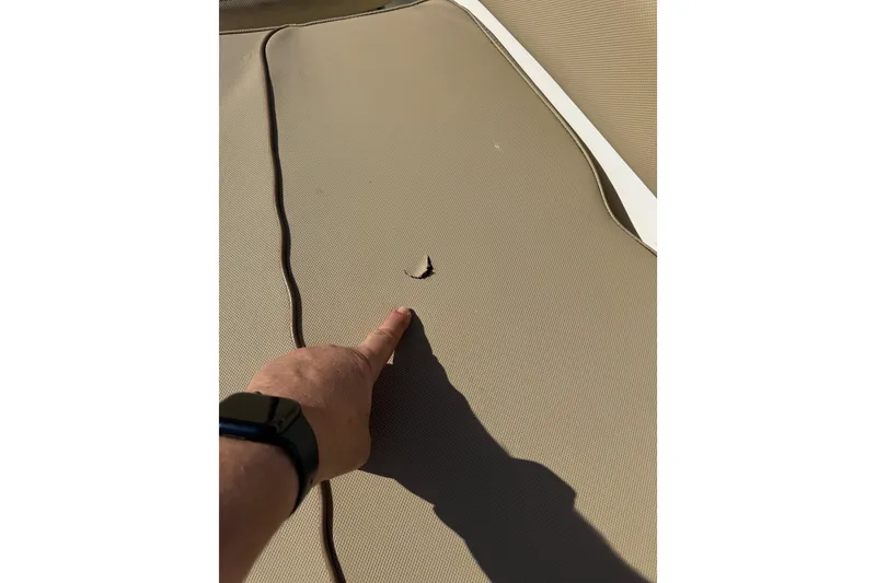 Slide: The Image of 2018 Sea Hunt Gamefish 27 boat seat with a small tear, finger pointing at damage. - 28