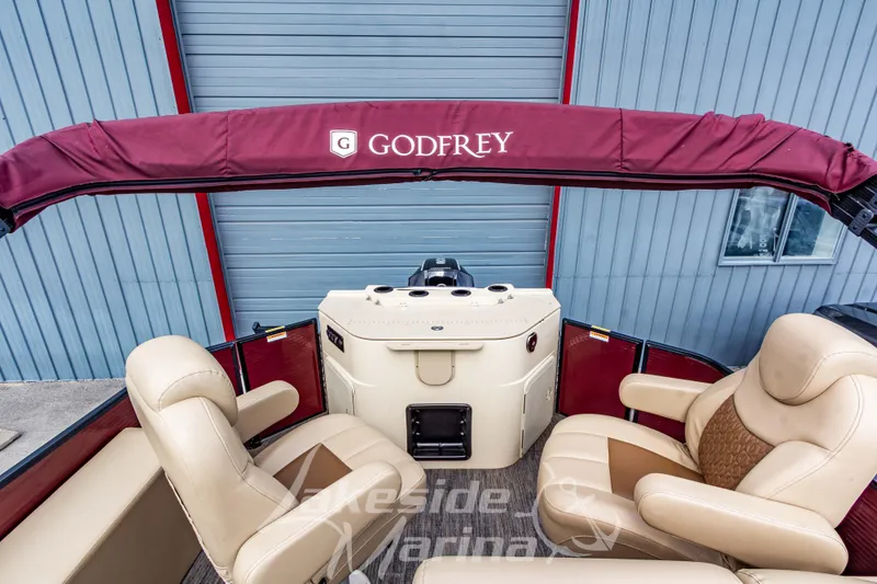 Slide: The Image of 2023 Godfrey Sweetwater 2286 FS boat interior with beige seating and maroon canopy. - 23