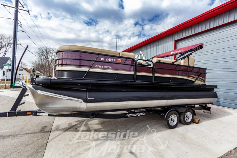 Slide: The Image of 2023 Godfrey Sweetwater 2286 FS pontoon boat on trailer, parked outside a marina. - 6