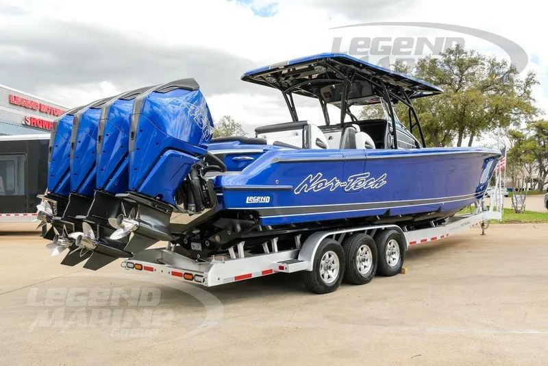 Slide: The Image of 2023 Nor-Tech 390 Sport Center Console boat on trailer, featuring triple outboard engines. - 6