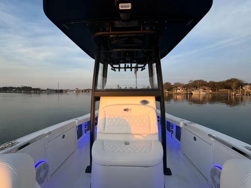 Slide: The Image of 2025 Crevalle 24 HCO boat interior with seating, on calm water at sunset. - 16
