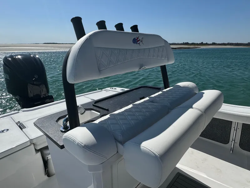 Slide: The Image of 2025 Crevalle 24 HCO boat with white seating, rod holders, and outboard motor on calm water. - 33