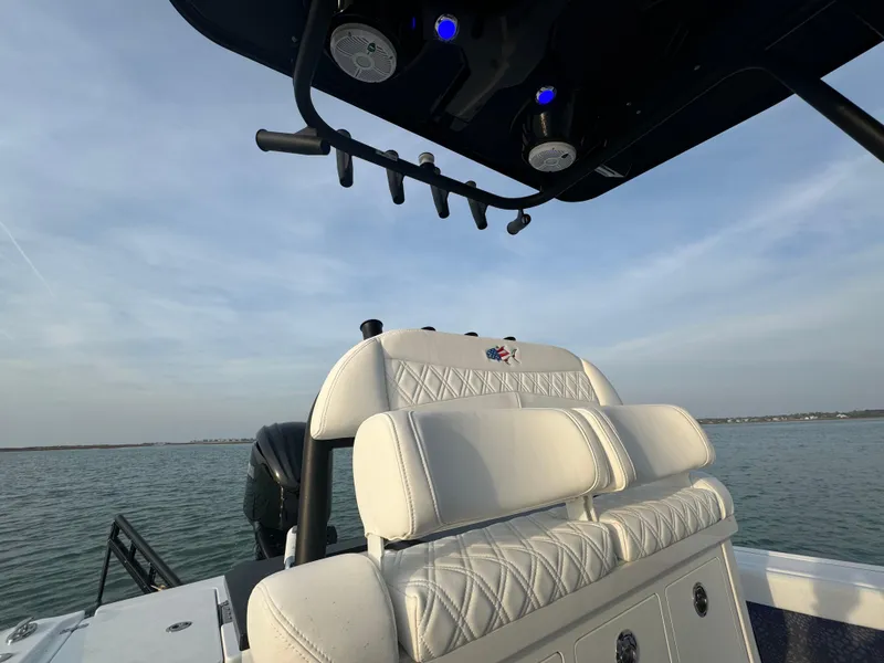 Slide: The Image of 2025 Crevalle 24 HCO boat interior with white seating and rod holders, on calm water. - 34